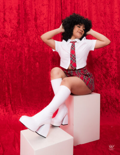 Sesión femenina en estudio con fondo rojo y vestuario colegial realizada por fotógrafo en Nuevo Laredo